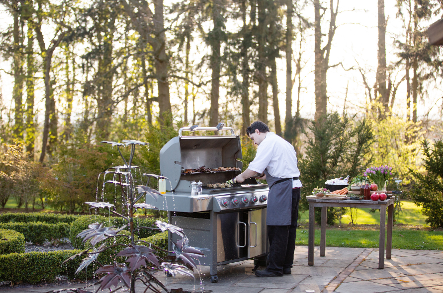 Chef preparing a barbecue outdoors in the gardens, showcasing catering options for weddings at Stone Manor.