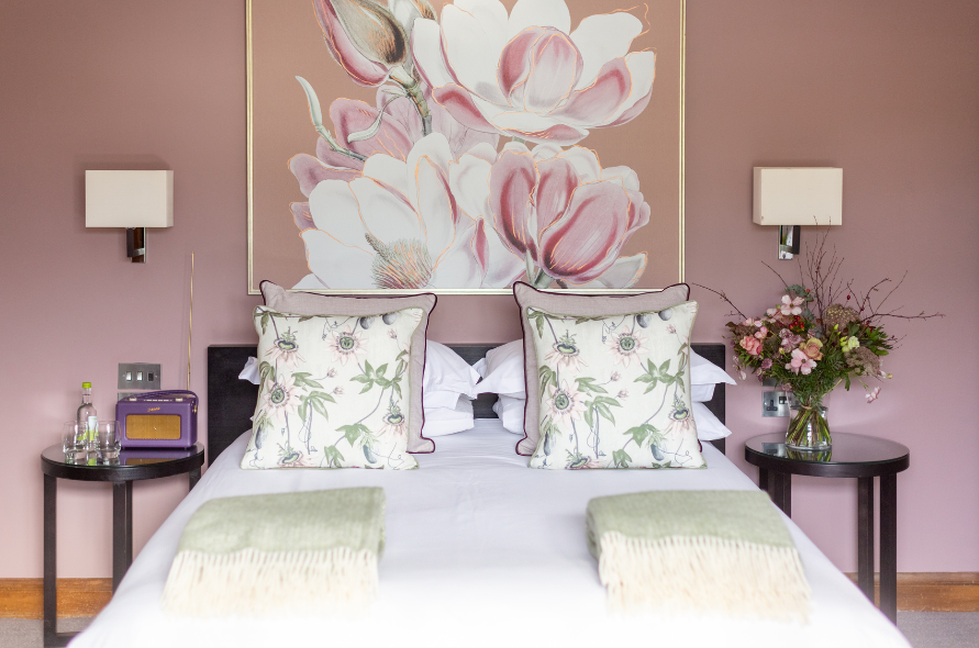King bed setup with floral decor and soft pink tones in a luxurious guest room at Stone Manor.