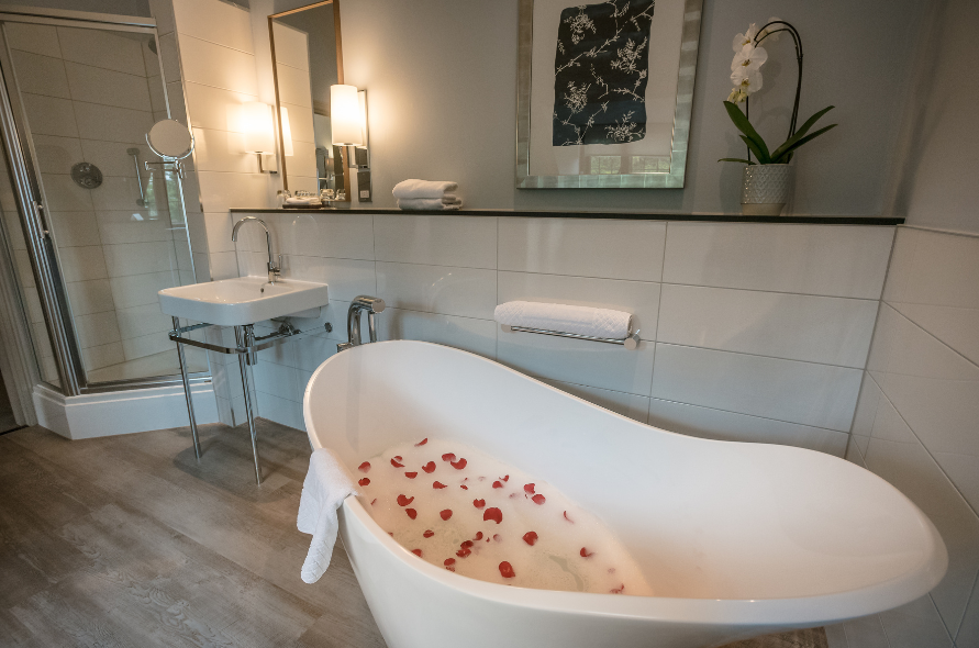 Elegant bathroom at Stone Manor featuring a freestanding bath with rose petals, perfect for a romantic retreat.