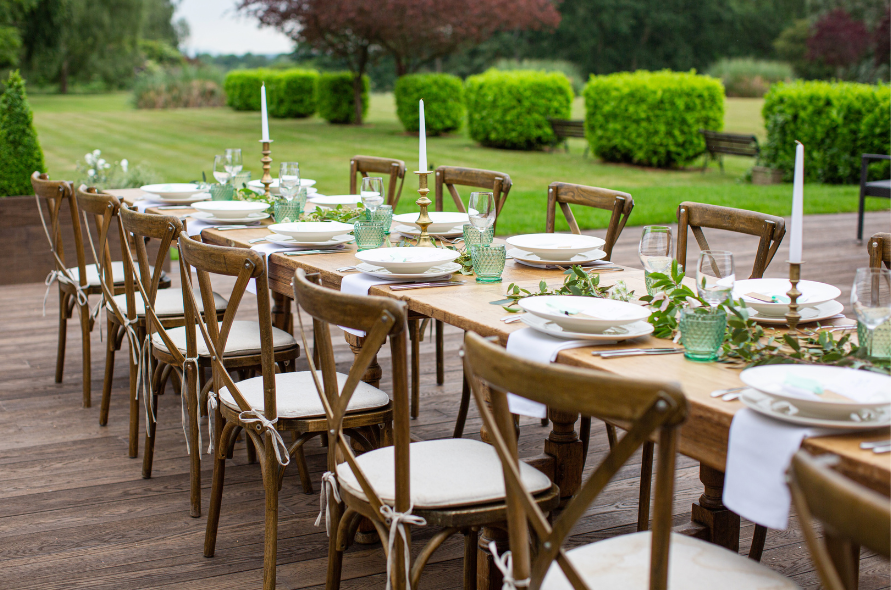 Outdoor reception setup with a long wooden table, elegant tableware, and greenery, showcasing weddings at Stone Manor.