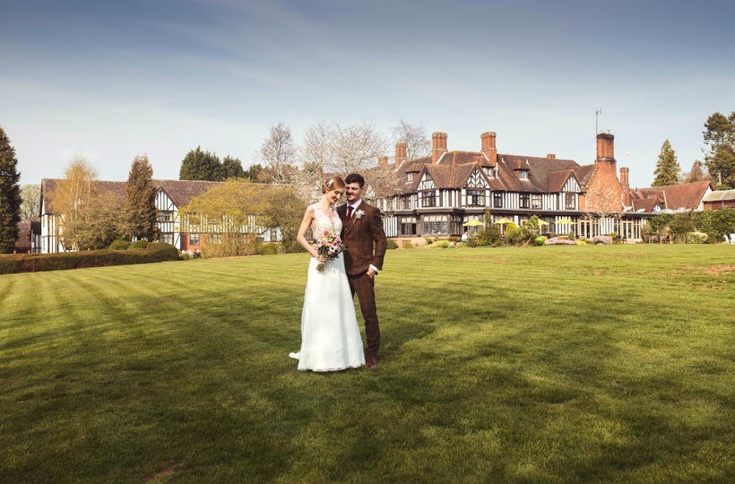 Bride and groom standing on the lawn in front of Stone Manor, capturing a picture-perfect wedding moment.