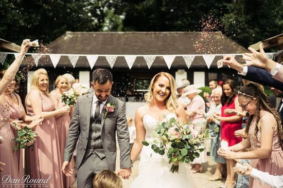 Bride and groom smiling as they walk hand-in-hand through a confetti shower, celebrating their big day at Stone Manor.