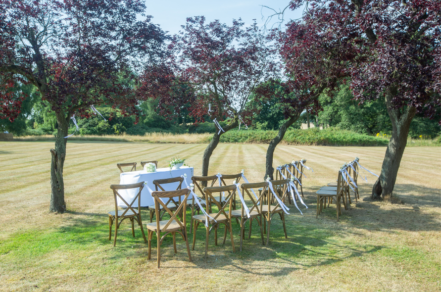 Outdoor table setup beneath blossoming trees, ideal for relaxed weddings at Stone Manor.

