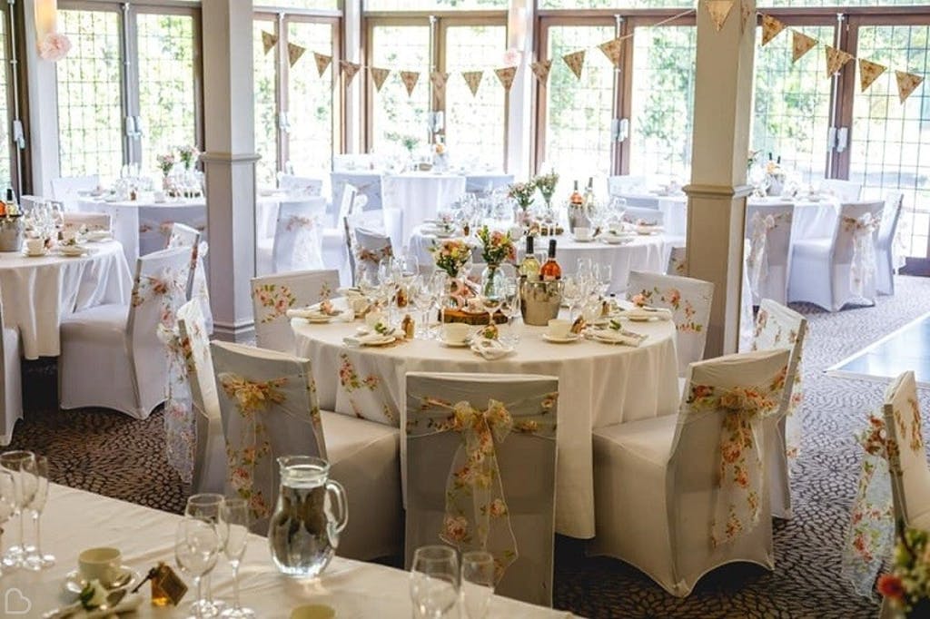 Beautifully decorated wedding reception setup with round tables, floral accents, and bunting for indoor weddings at Stone Manor.