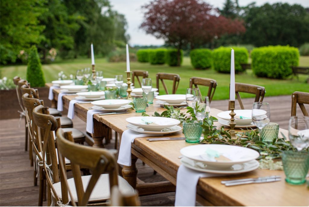 Rustic outdoor wedding table setup on the lawn, showcasing natural wood décor and soft green accents for weddings at Stone Manor.