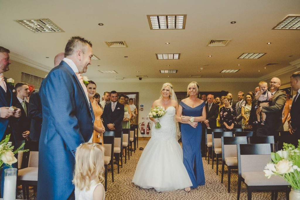 Bride walking down the aisle with her mother in an indoor ceremony room at Stone Manor